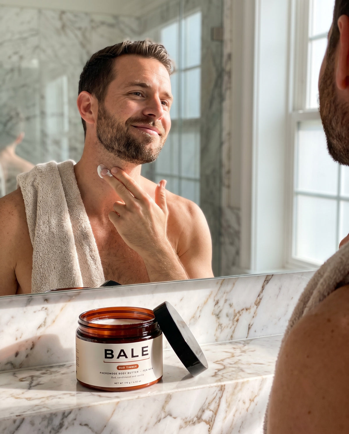 A man applying Oud Timber body butter in a bright bathroom
