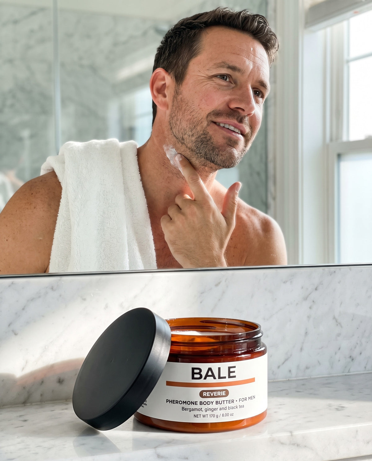 A man applying Reverie body butter in a bright bathroom