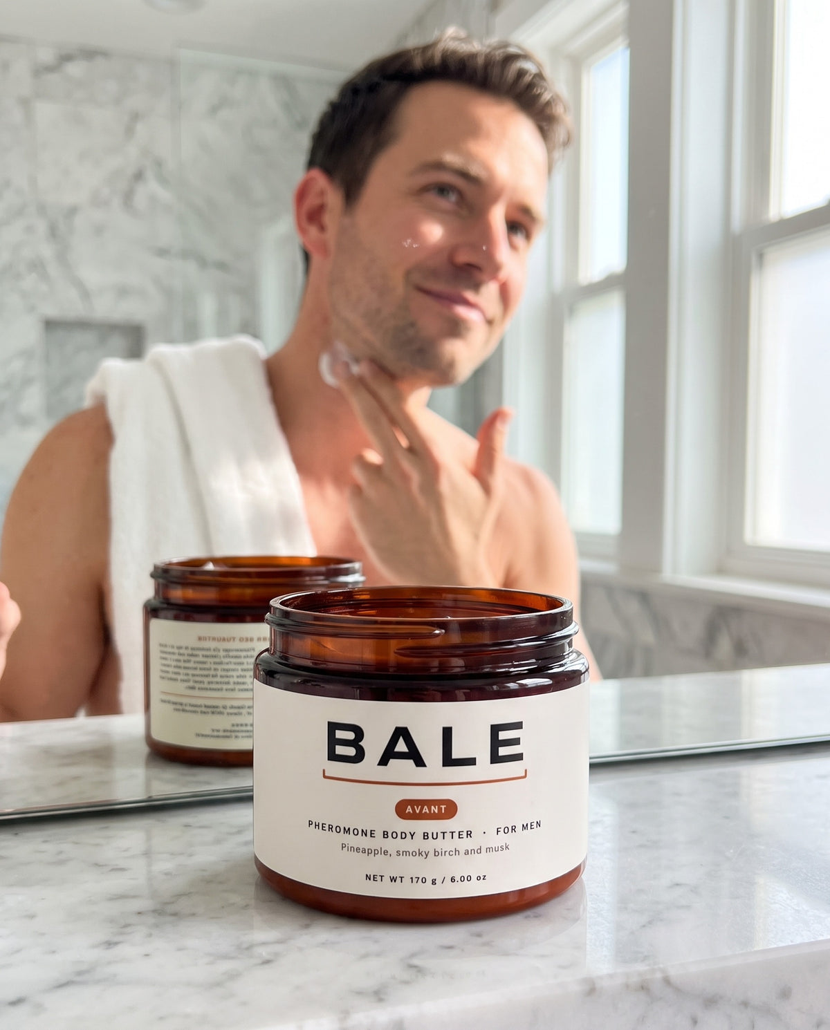 A man applying Avant body butter in a bright bathroom