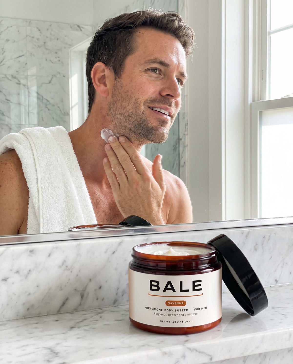 A man applying Savanna body butter in a bright bathroom