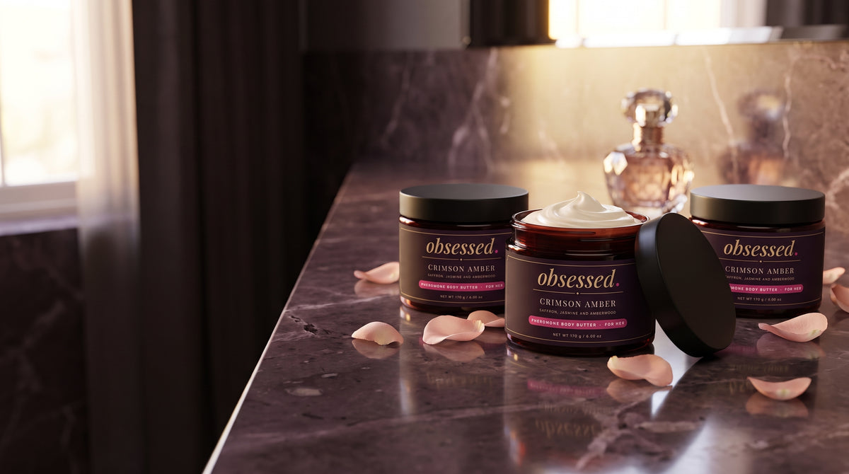 Three Crimson Amber jars on a dark marble bathroom counter with rose petals