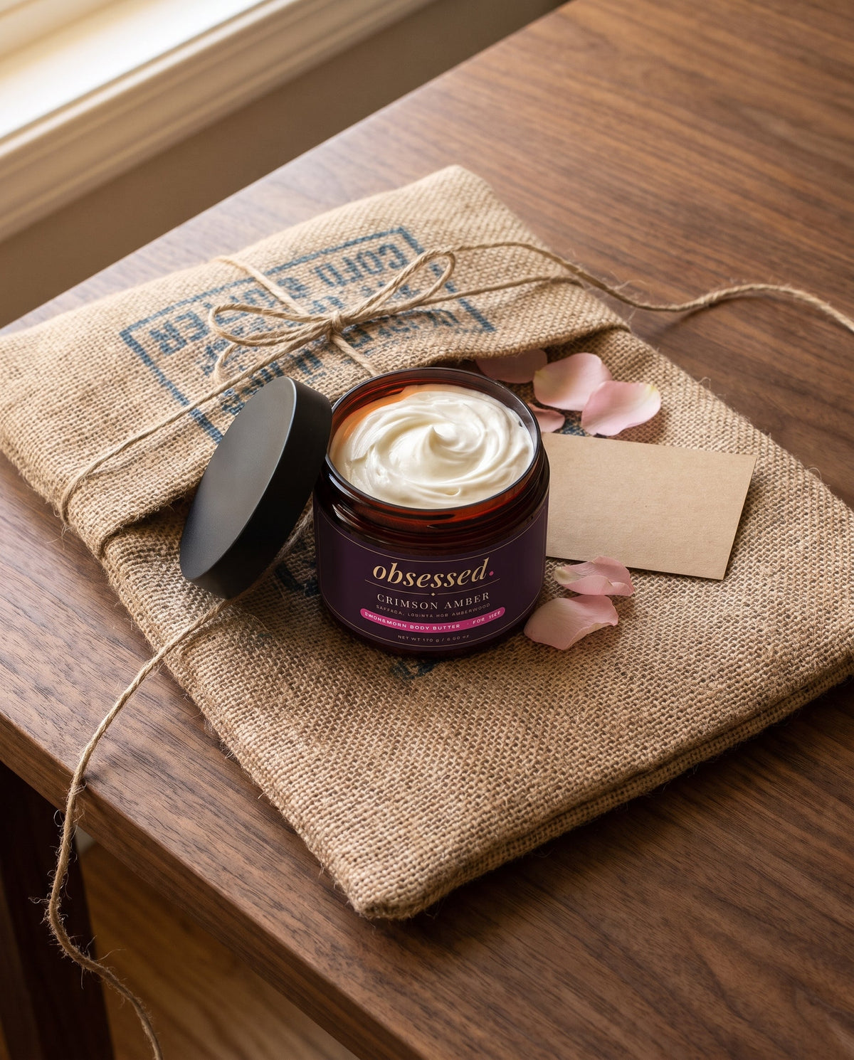 An Obsessed order wrapped in a coffee sack and tied with twine, opened to show the jar and a card