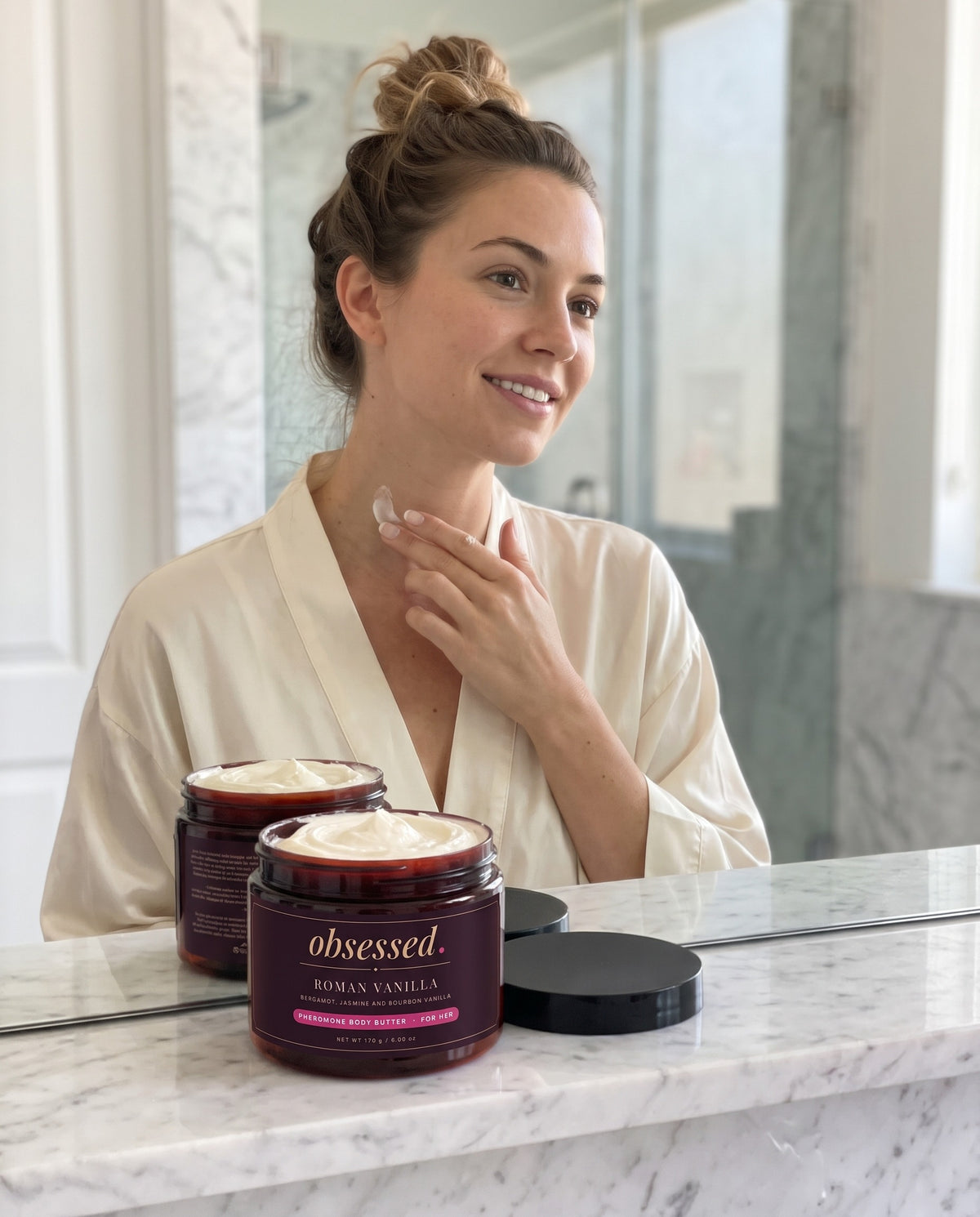 A woman smoothing Roman Vanilla body butter along her collarbone and neck